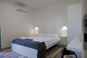 a white bedroom with a bed and a table at Essentia Rooms & Relax in Vasto