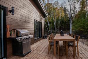 un patio avec une table et un grill et une table et des chaises dans l'établissement Le Roselin Exitchalets Spa & Lake, à Notre-Dame-de-la-Merci