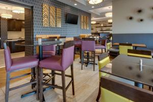 a restaurant with purple chairs and tables and a tv at Drury Inn & Suites Pittsburgh Airport Settlers Ridge in Pittsburgh