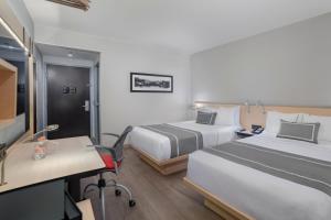 um quarto de hotel com duas camas e uma secretária em City Express Plus by Marriott Insurgentes Sur em Cidade do México