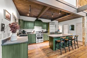 a kitchen with green cabinets and a island with bar stools at Private Hideaway with Hot Tub - Stylish & Serene in Ellicottville