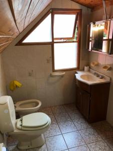 a bathroom with a toilet and a sink and a window at CABAÑA EL REMANSO in Villa Pehuenia