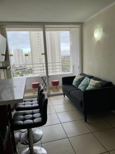 a living room with a couch and a large window at Lindo departamento a pasos de la playa in Coquimbo