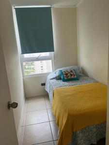 a small bedroom with a bed and a window at Lindo departamento a pasos de la playa in Coquimbo