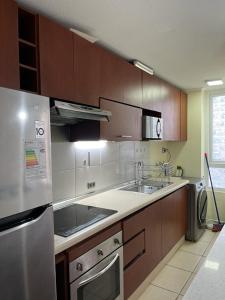 una cocina con armarios de madera y electrodomésticos de acero inoxidable en Lindo departamento a pasos de la playa, en Coquimbo