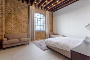 a bedroom with a bed and a brick wall at Luxury 1Bed In Converted Warehouse Next To London Excel in London