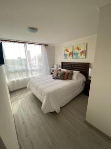une chambre avec un grand lit avec des draps blancs dans l'établissement Departamento para 6 personas, à Iquique