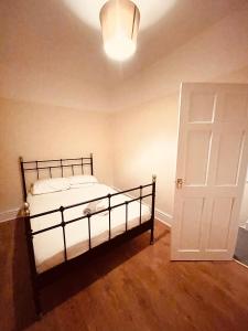 1 dormitorio con cama y puerta blanca en 5 STAR BIG SPACIOUS 2 BEDROOM HOUSE, SLEEPS 8, FREE STREET PARKING, EASY ACCESS LOCK BOX ENTRY, 2 minute drive from city centre, en Liverpool