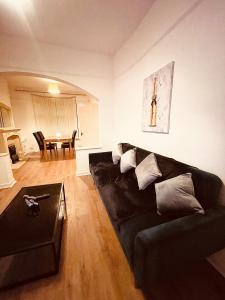 a living room with a black couch and a table at BIG SPACIOUS 2 BEDROOM HOUSE, SLEEPS 8, FREE STREET PARKING, EASY ACCESS LOCK BoX ENTRY, NO PARTIES! in Liverpool