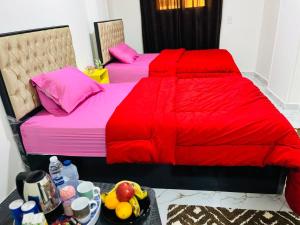 two beds with red comforters and a bowl of fruit at Four pyramids Guest house pyramids View in Cairo