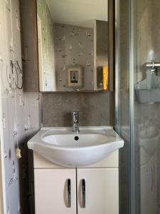 a bathroom with a white sink and a mirror at Aurora luxury beach lodge in Lossiemouth +22 photos