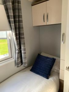 a small bedroom with a bed and a window at Aurora luxury beach lodge in Lossiemouth