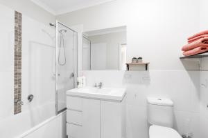 a white bathroom with a toilet and a sink at Stylish & Modern Townhouse in Canberra in Harrison
