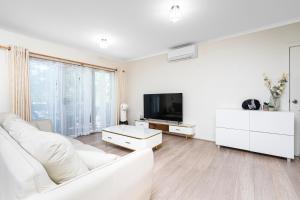 a white living room with a white couch and a tv at Stylish & Modern Townhouse in Canberra in Harrison