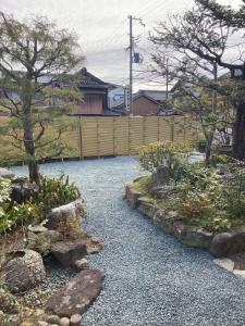 un jardin avec des rochers, des arbres et une clôture dans l'établissement Ichie, à Tanabe