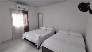een slaapkamer met 2 bedden en een raam bij Hostal torres del caribe in San Bernardo del Viento