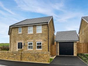 a brick house with a garage in a driveway at Crawshaw Cottage in Buxton