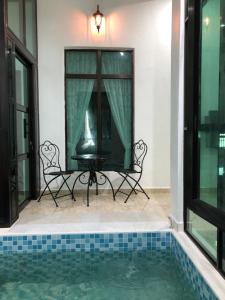 um pátio com uma mesa e cadeiras ao lado de uma piscina em D”One House em Kota Bharu