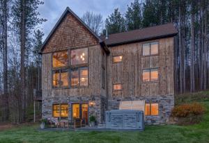 a barn style house with a wrap around porch at New & Stunning Chalet! Reno'd, Hot-Tub, Barrel Sauna, Slope Views, Fire Pit in Ellicottville
