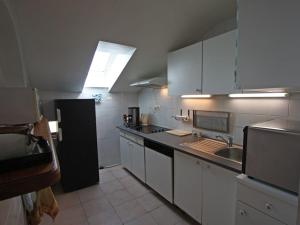 een keuken met witte kasten en een zwarte koelkast bij Gîte Granges-Aumontzey-Granges-sur-Vologne, 3 pièces, 5 personnes - FR-1-589-122 in Granges-sur-Vologne