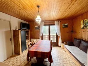 a dining room with a table and a couch at Chalet cosy en bordure de forêt avec wifi, terrasse et équipements complets à Rochesson - FR-1-589-235 in Rochesson
