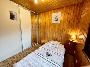 a bedroom with a bed in a wood paneled room at Chalet cosy en bordure de forêt avec wifi, terrasse et équipements complets à Rochesson - FR-1-589-235 in Rochesson