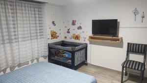 una camera da letto con una culla e una TV a muro di Casa a 21 minutos de aeropuerto de Ezeiza tranfer opcional amplio parque para mascotas a Ezeiza