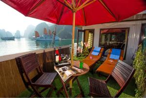 un patio con una mesa y sillas con una sombrilla roja en Royal Palace Cruise en Ha Long