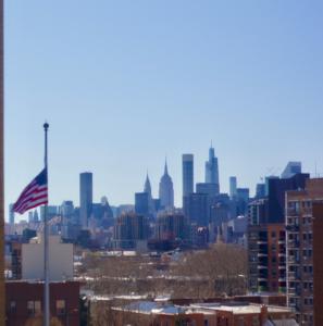 an american flag flying in front of a city skyline at 10 Minutes from NYC - Astoria LIC CityView in Steinway