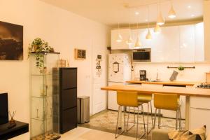 uma cozinha com armários brancos e um balcão com cadeiras amarelas em Cosy 38 m love nest near Centquatre-Paris em Paris