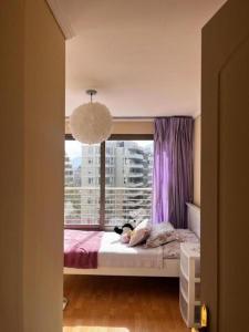 um quarto com uma cama e uma janela com cortinas roxas em Habitación Acogedora en Vitacura em Santiago
