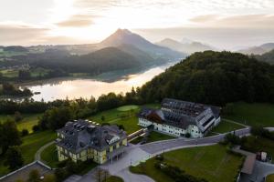 an aerial view of a building on a hill next to a river at Arabella Jagdhof Resort am Fuschlsee, a Tribute Portfolio Hotel in Hof bei Salzburg