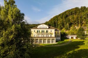 a large house on a hill with a green yard at Arabella Jagdhof Resort am Fuschlsee, a Tribute Portfolio Hotel in Hof bei Salzburg