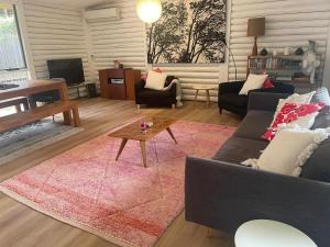 una sala de estar con un sofá y una mesa en Lorne Groovy Ocean View Log House, Pet Friendly, FREE WIFI wine & chocolates kangaroos in the evening, en Lorne