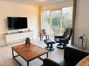 a living room with two chairs and a flat screen tv at Bungalow in Makkum near Lake Beach in Holle Poarte