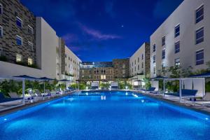 una grande piscina di notte di fronte agli edifici di City Express Plus by Marriott Cancun Aeropuerto Riviera a Cancún