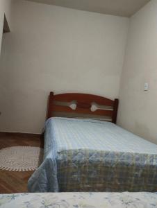 1 dormitorio con 1 cama con cabecero de madera en kitnet sao thome das letras en São Tomé das Letras
