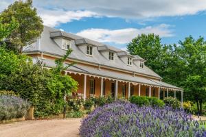Fitzroy Inn Historic Retreat Mittagong في ميتاغونغ: منزل كبير أمامه زهور أرجوانية