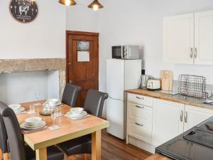 a kitchen with a table and chairs and a kitchen with a refrigerator at Cozy Cow Cottage in Belford
