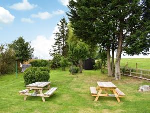 two picnic tables sitting in the grass next to a tree at Cozy Cow Cottage in Belford