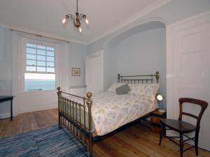 a bedroom with a bed and a table and a window at Ty Mair in Tenby