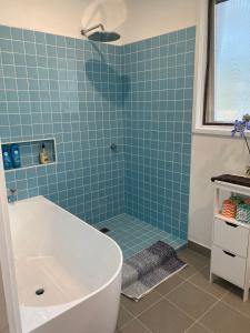 a blue tiled bathroom with a tub and a sink at Lorne Groovy Ocean View Log House, Pet Friendly, FREE WIFI wine & chocolates kangaroos in the evening in Lorne