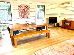 a living room with a wooden table and a bench at Lorne Groovy Ocean View Log House, Pet Friendly, FREE WIFI wine & chocolates kangaroos in the evening in Lorne