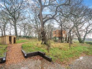 un banco en un campo con árboles y un edificio en The Treehouse Caerlaverock - Uk45028, en Carsethorn