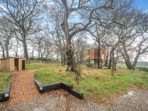 a bench in a field with trees and a building at The Treehouse Caerlaverock - Uk45028 in Carsethorn