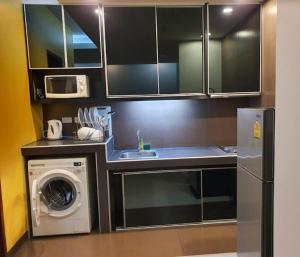 eine Küche mit einer Spüle und einer Waschmaschine in der Unterkunft Lasalle Park Serviced Apartment at Lasalle 75 in Bangna