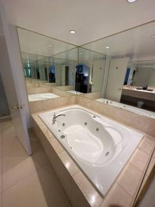 een grote badkamer met een bad en een grote spiegel bij Relax & Rejuvenate at 2BR Retreat with Pool & Gym in Shanty Bay