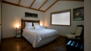 a bedroom with a bed and a chair and a window at Wanderers Cottage in Woodbridge