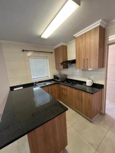 a kitchen with wooden cabinets and a black counter top at Vigne Palm Inn apartment in Gqeberha