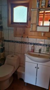 baño con aseo y lavabo y ventana en Coñaripe Kuyen Mapu Cabañas en Coñaripe